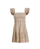 A tan smocked top mini dress with ruffle straps and sequenced detailing. Featured against a white wall background.