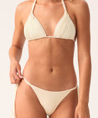 Woman wearing a cream bikini set on a plain background