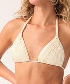 Close-up of a woman wearing a cream bikini top with a plain background