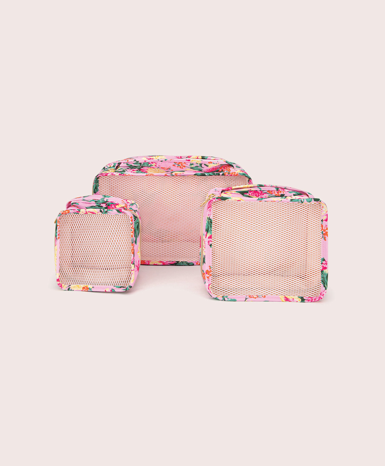Set of three floral-patterned mesh packing cubes on a light pink background