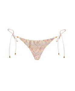 A multi-colored print triangle bikini bottom with gold details. Featured against a white wall background.