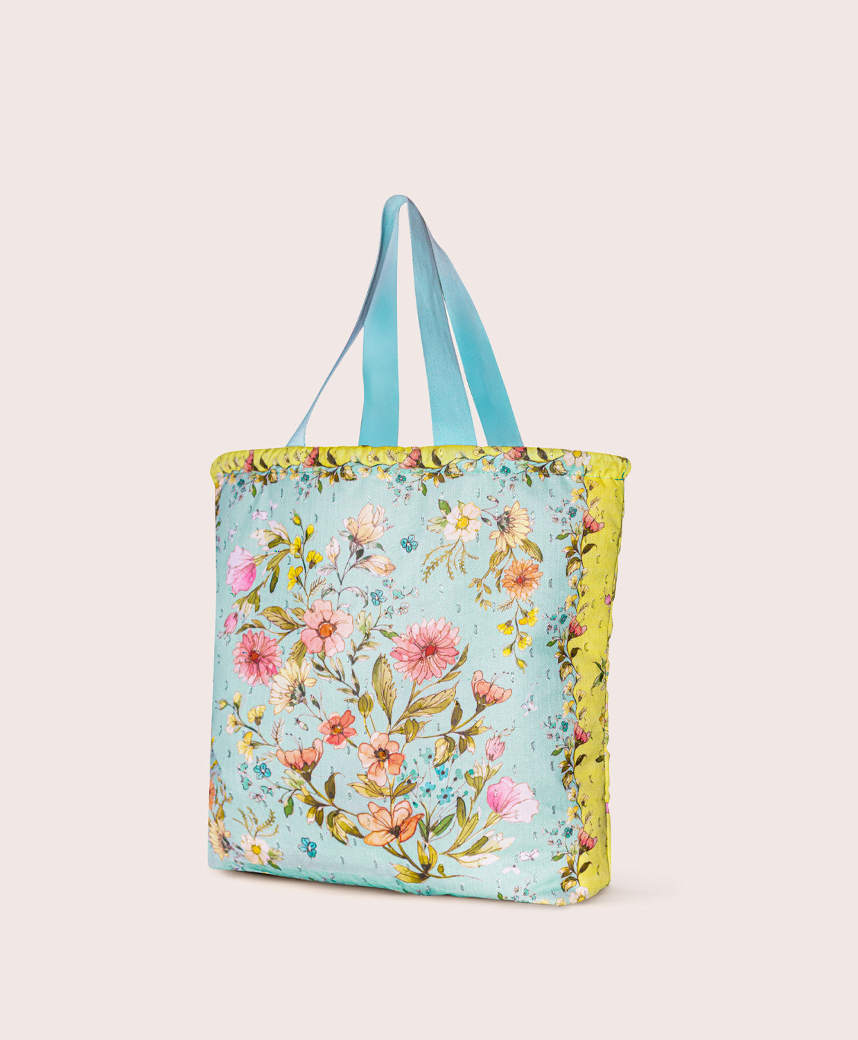 Floral tote bag with blue handles on a plain background