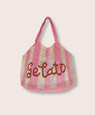 A pink striped purse/tote with letters that says "Gelato" against a white wall.