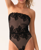 Woman wearing a black strapless swimsuit on a white background