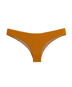 An orange ruched bikini bottom in cheeky coverage. Featured against a white wall background.