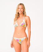 A woman wearing a light blue floral bikini set with a white crochet knit trim in front of a white background.