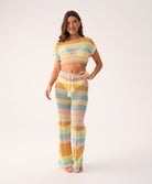 Woman wearing a colorful striped crochet outfit on a white background