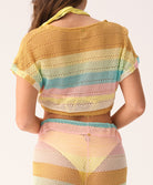 Woman wearing a colorful crochet top and pant set on a plain background