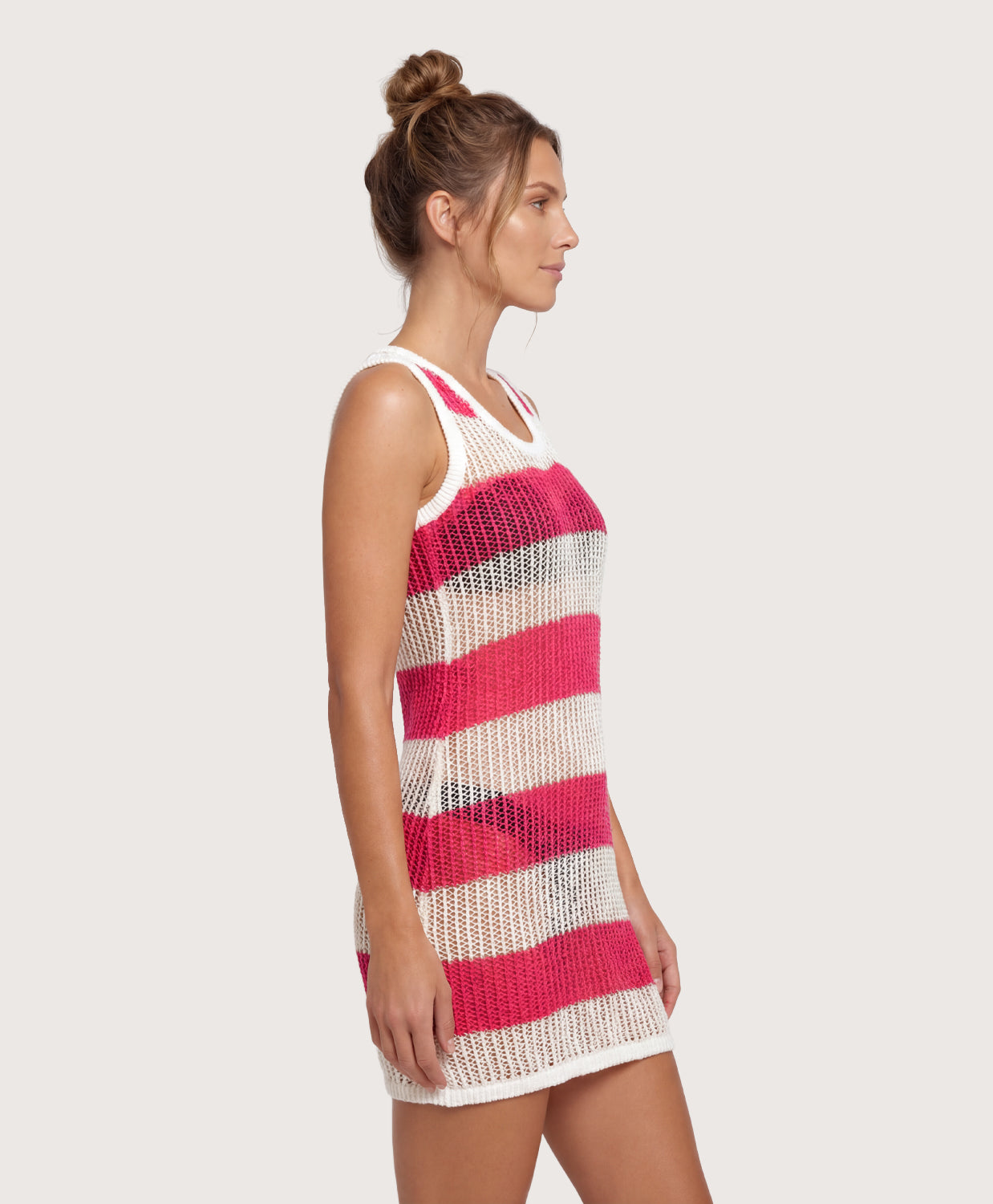 Woman wearing a pink and white striped crochet dress on a plain background