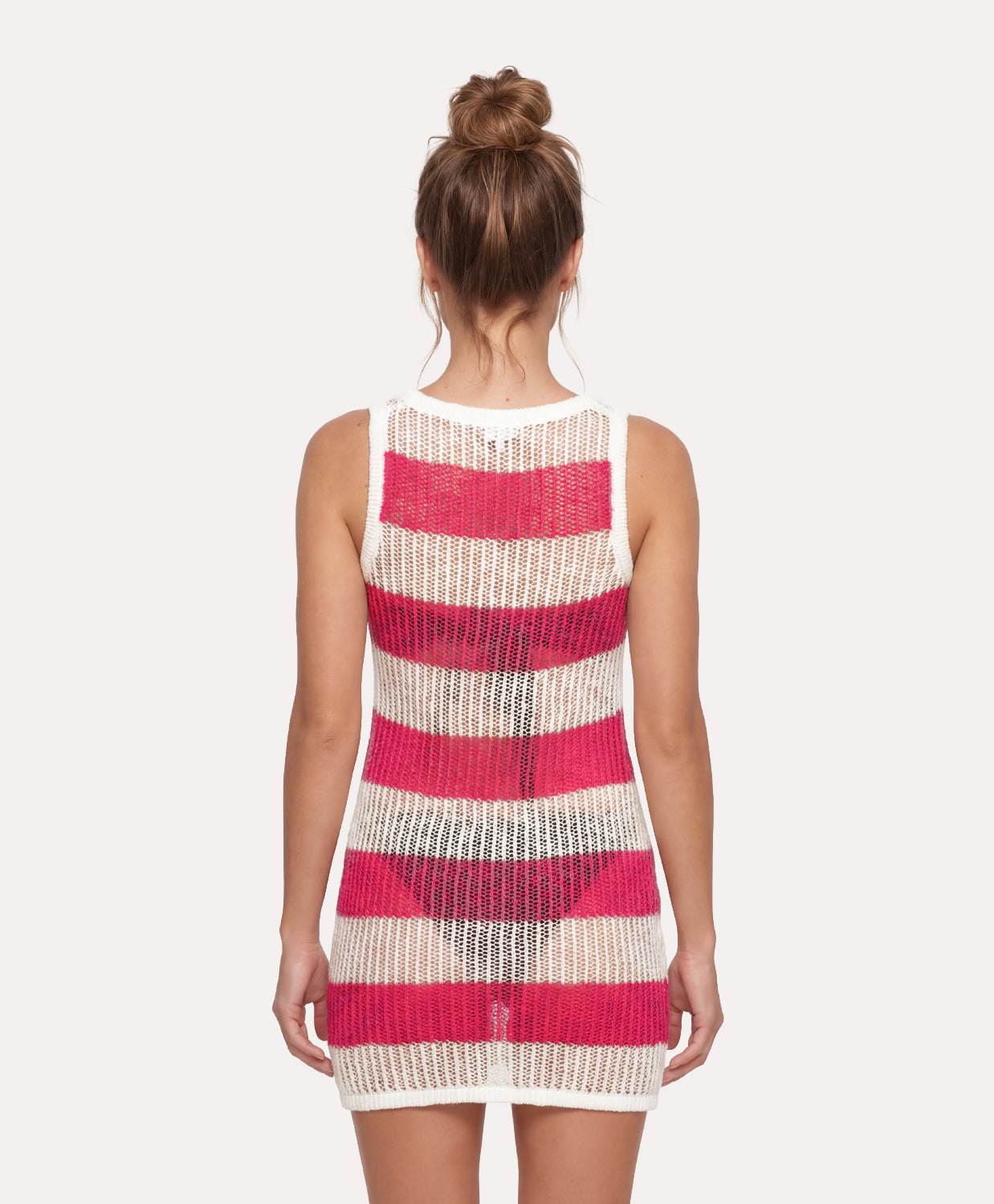 Woman wearing a sleeveless dress with pink and beige striped pattern on a white background