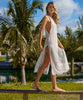 Blonde woman wearing an ivory sleeveless cover up with scalloped lace detailing stands on a railing.