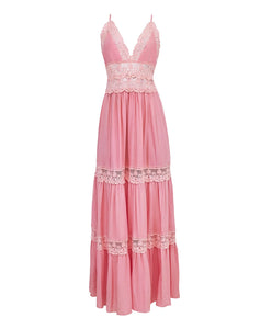 A floor length pink dress against a white wall. 