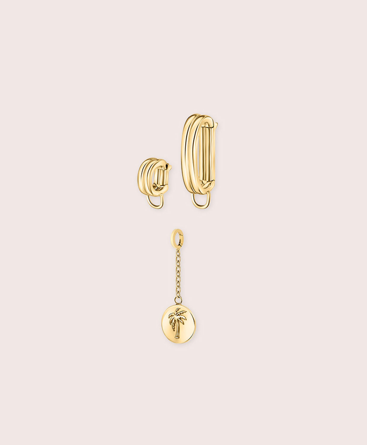 Gold jewelry piece with palm tree details against a white wall.