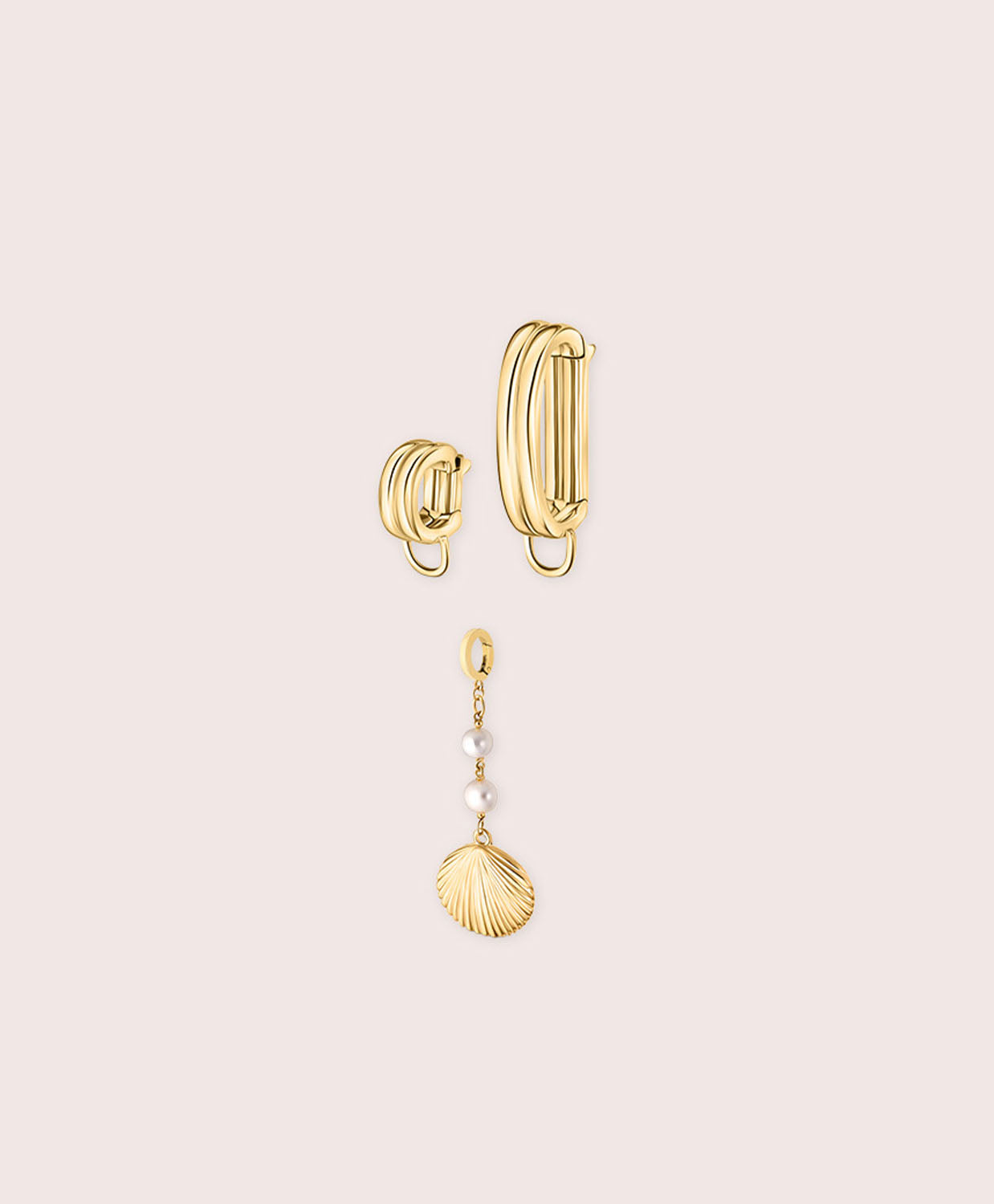 Gold bikini jewelry with a shell against a white wall.