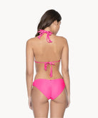 Back view of woman in hot pink macrame bikini against white wall.