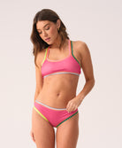 Woman wearing a pink bikini with colorful crochet trim on a white background