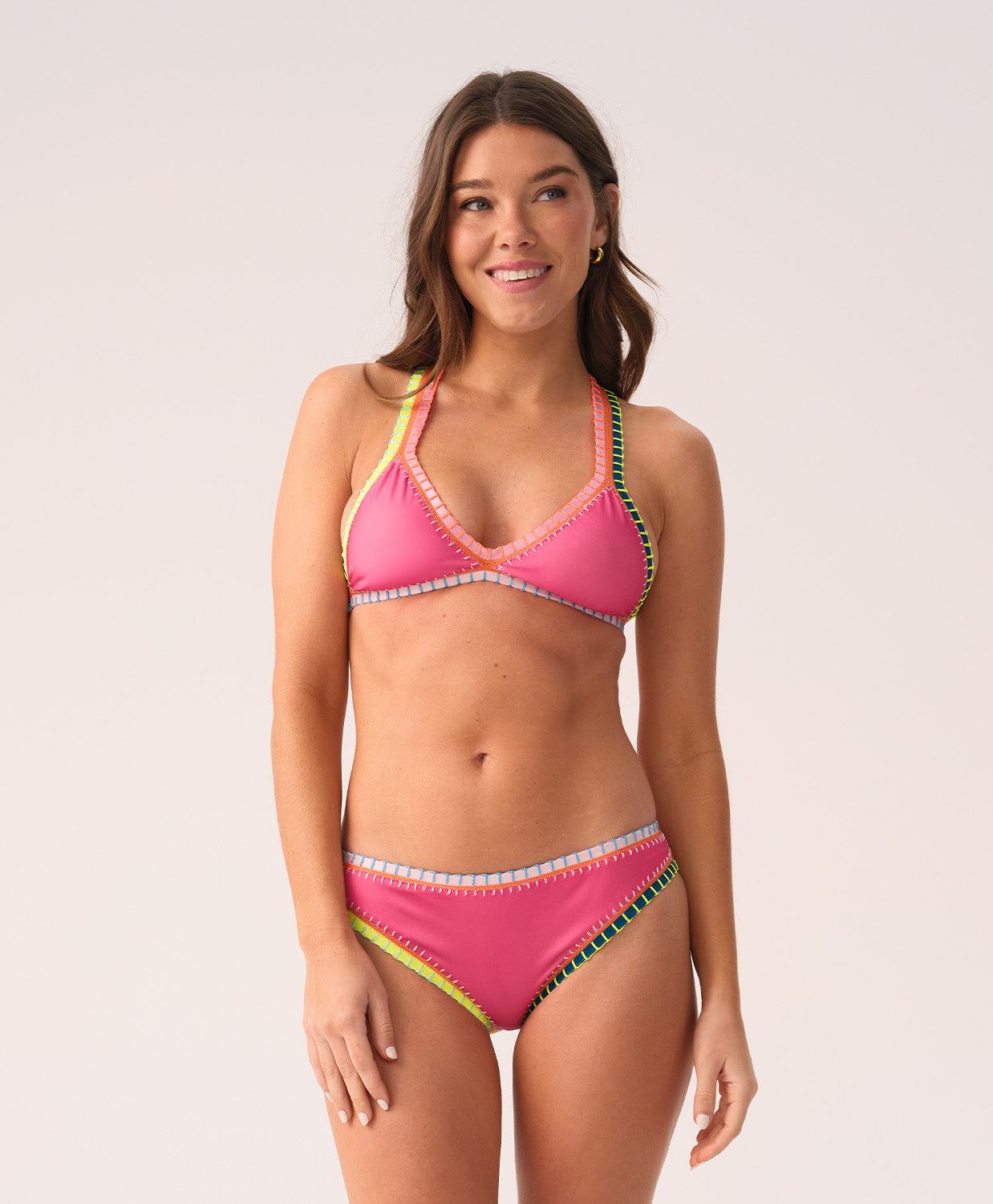 Woman wearing a pink bikini with colorful crochet trim on a white background