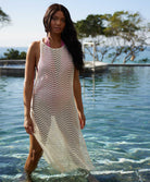 A woman wearing an ivory sleeveless cover up with scalloped lace detailing standing in a pool.