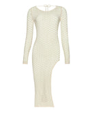 A long sleeve ivory dress with crochet details against a white wall.