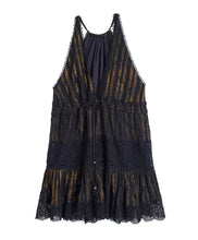 A reversible black dress with embroidered details. Featured against a white wall background.