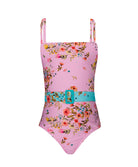 A light pink kids one piece swimsuit with a floral pattern against a white wall. 