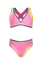 A pink bikini with colorful embroidered trim against a white wall.