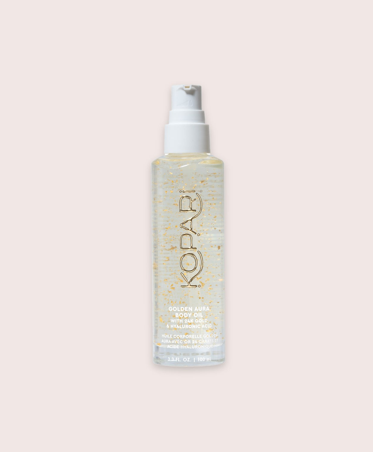 A tube of body oil with gold glitter against a white wall.