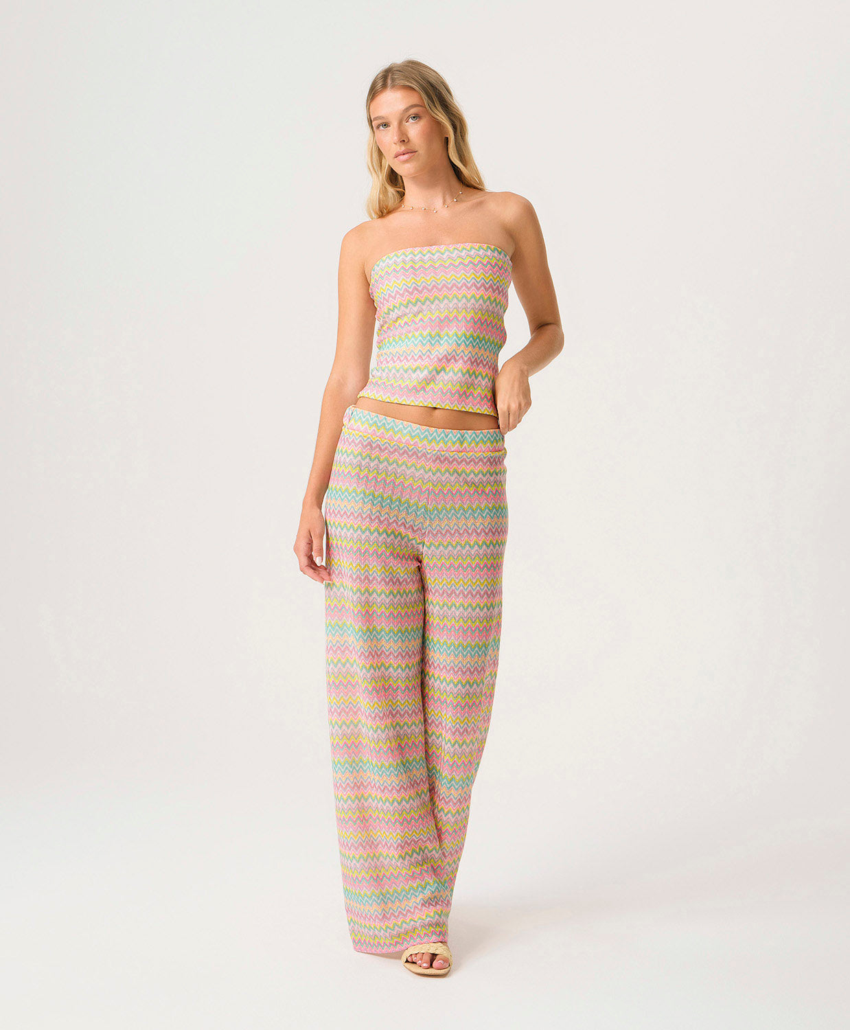 Woman wearing a pastel striped strapless top and pants on a white background