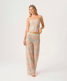 Woman wearing a pastel striped strapless top and pants on a white background