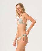 Woman wearing a colorful triangle bikini against a white background