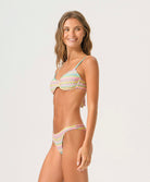 Woman wearing a striped bikini with a zig zag pattern against a white wall.