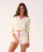 Woman wearing a white outfit with pink accents on a white background