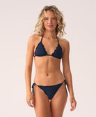 Woman wearing a navy blue bikini against a plain background