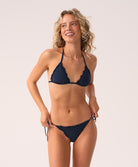 Woman wearing a navy blue bikini against a plain background