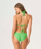Woman wearing a green triangle top bikini against a white background