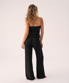 Woman wearing a black strapless jumpsuit on a white background