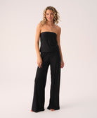 Woman wearing a black strapless jumpsuit on a white background