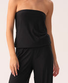 Woman wearing a black strapless jumpsuit against a white background