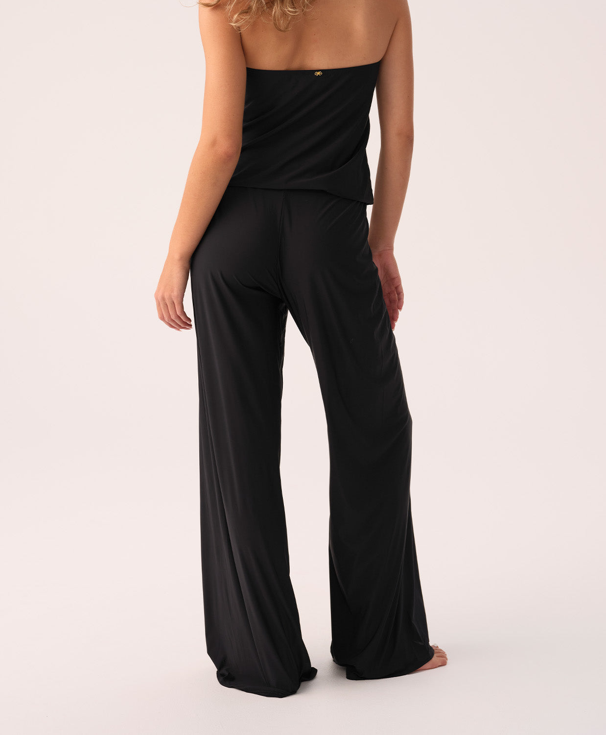 Black strapless jumpsuit worn by a woman on a white background