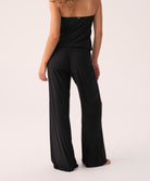 Black strapless jumpsuit worn by a woman on a white background