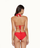 Back view of brunette woman wearing a red bikini in front of a white background. 