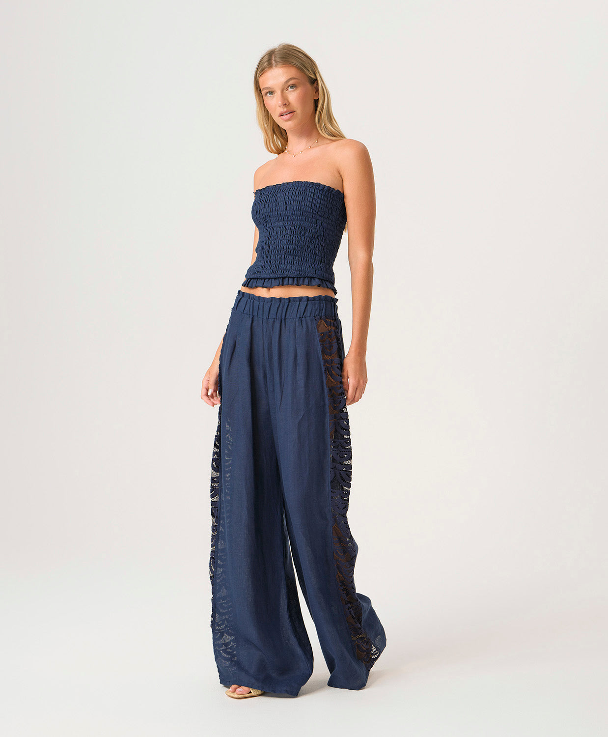 Woman wearing a navy strapless top and wide-leg pants on a white background