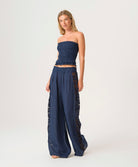 Woman wearing a navy strapless top and wide-leg pants on a white background