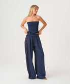 Woman wearing a navy strapless top and wide-leg pants on a white background