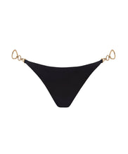 A black bikini bottom with gold details against a white wall. 