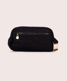 A black lace crossbody bag against a white wall. 