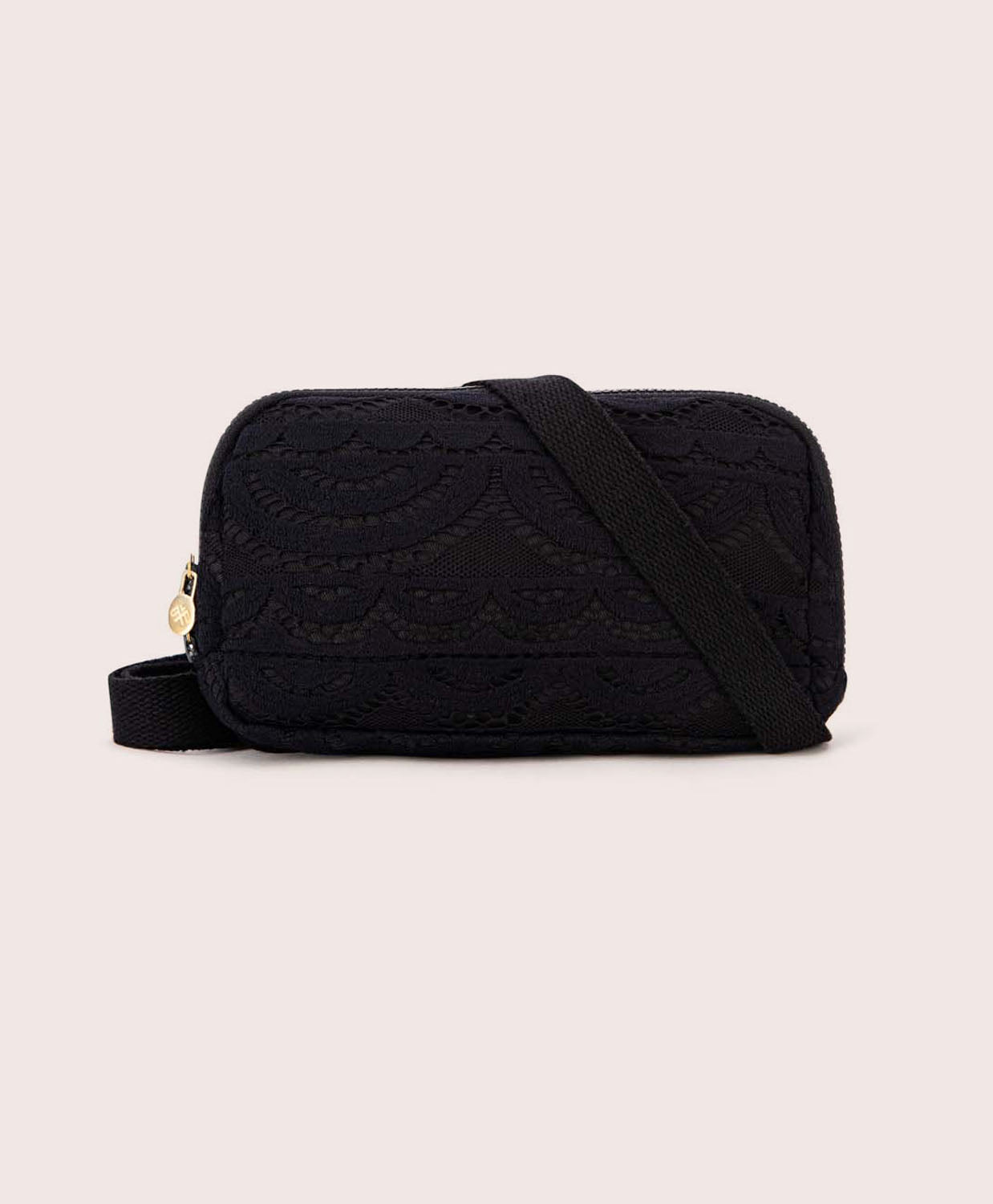 A black lace crossbody bag against a white wall. 