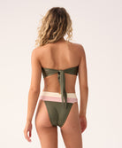 Woman wearing a green bikini with a white and pink bottom on a light background
