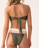 Woman wearing a green bikini with a white and pink bottom on a plain background