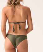 Woman wearing a green bikini with a halter top and tie back on a white background